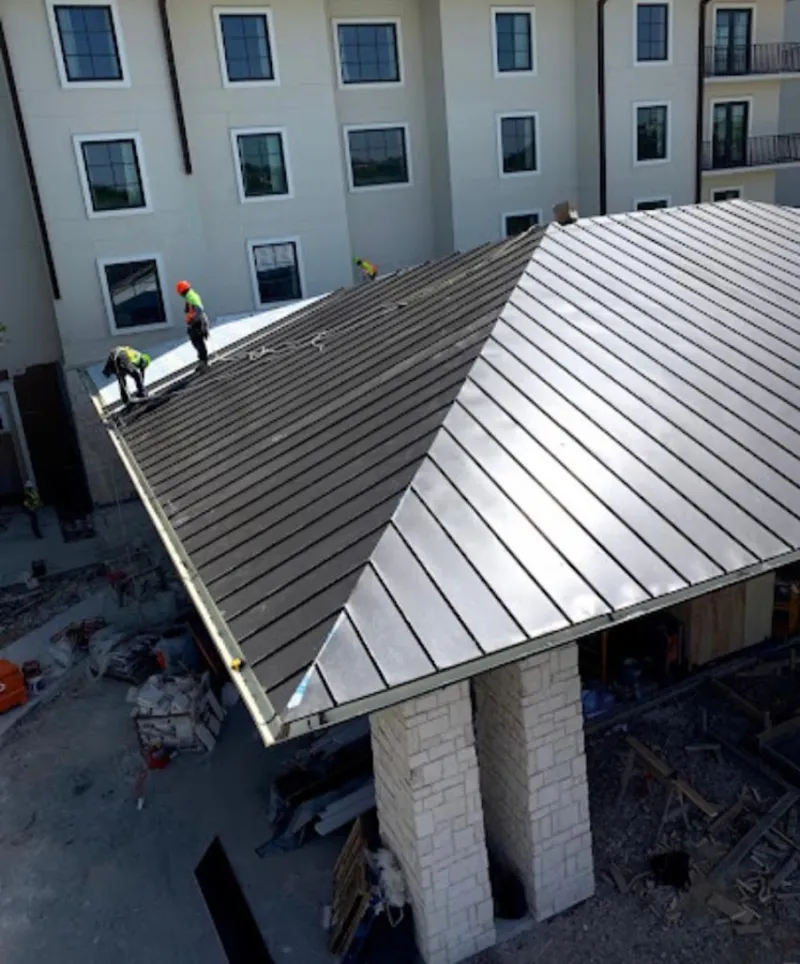 Crew installing standing seam metal roof panels on a commercial project in Brookfield
